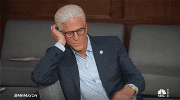 TV gif. Ted Danson as Neil in Mr. Mayor wears thick rimmed glasses. He rests his head in his palm as he flicks his wrist to examine a gold watch. 