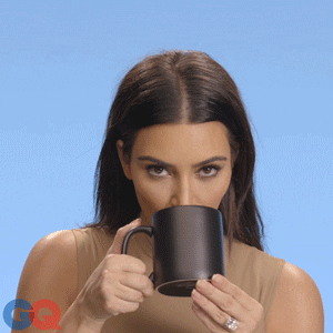 Celebrity gif. Kim Kardashian looks at us as she sips tea from a cup.