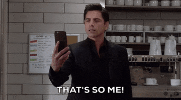TV gif. John Stamos as Jimmy in Grandfathered. He holds his phone far from his face, reading it slowly before breaking out into a smile and saying, "That's so me," and running off with a wide smile. 