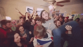 Music video gif. A scene from Donovan Wolfington's music video for Keef Ripper. A man is crowd surfing at a house party and the house looks packed and chaotic.