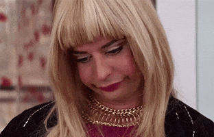 Celebrity gif. Nick Kroll dressed as a blonde woman is staring downwards, lips pursed in disappointment and eyes wide in annoyance.