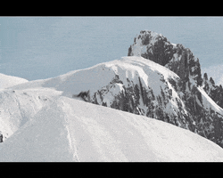 Sports gif. Snowboarder Billy Morgan spins as he flies over the ledge of hill, then crash lands and slides down the snowy slope.