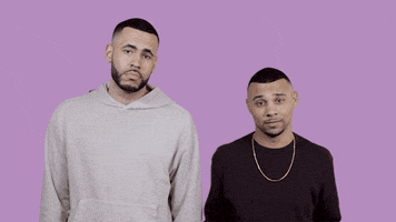 Celebrity gif. Hip hop duo 99 Percent lift their hands and shrug their shoulders, tilting their heads towards each other.