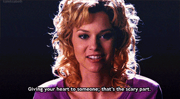 TV gif. Hilarie Burton as Peyton in One Tree Hill. She's sitting in a dark room and a warm smile fills her face as she says, "Giving your heart to someone. That's the scary part."