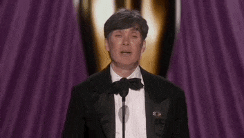 Oscars 2024 GIF. Cillian Murphy wins Best Actor. He triumphantly raises his arm while clutching onto the trophy. 
