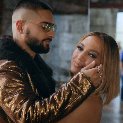 Movie gif. Maluma as Bastian in Marry Me kisses Jennifer Lopez as Kit on the cheek, cupping her face in his hands as she turns toward us with a soft smile.